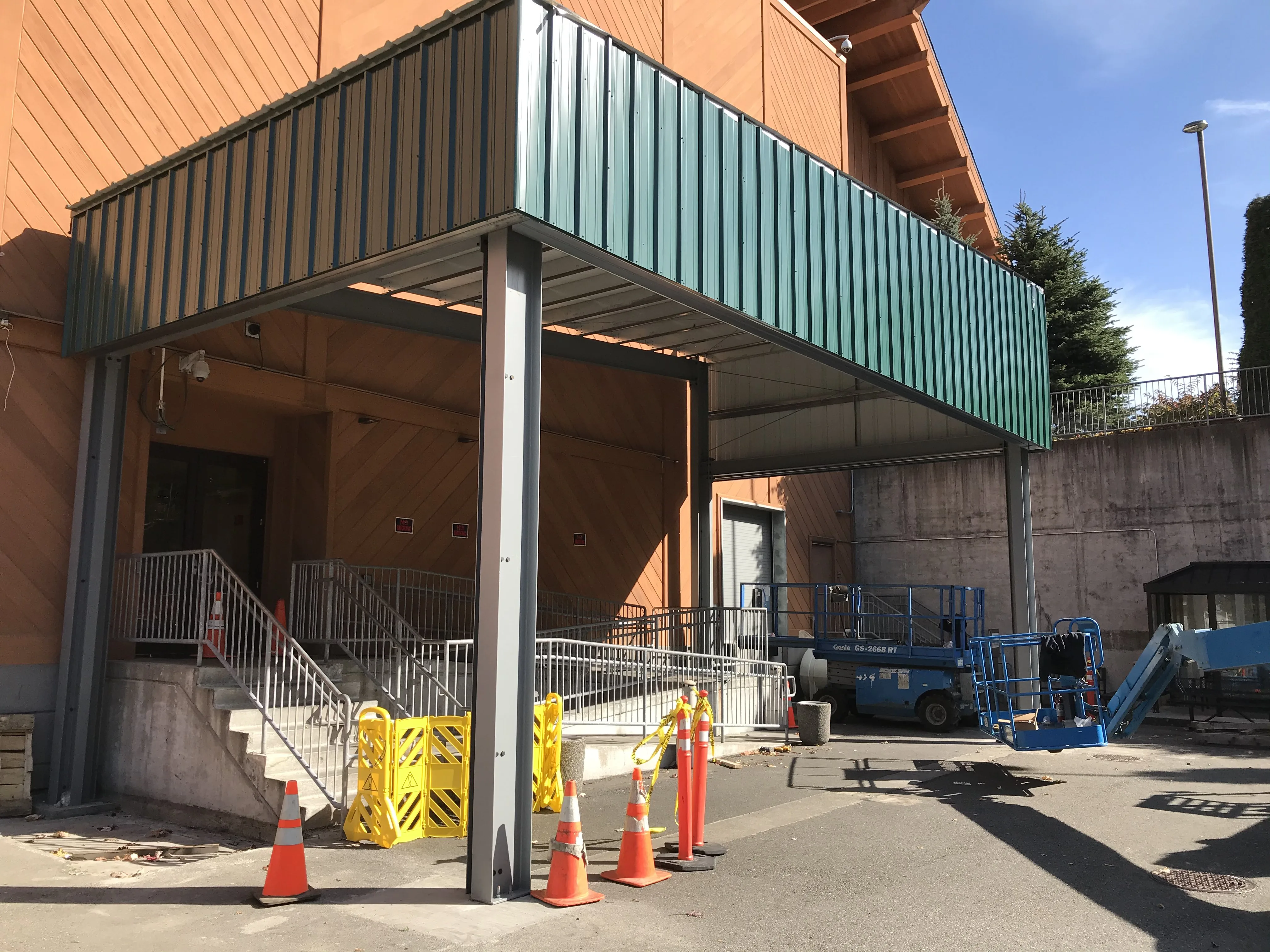 Green metal canopy with corrugated siding and ADA ramp near completion