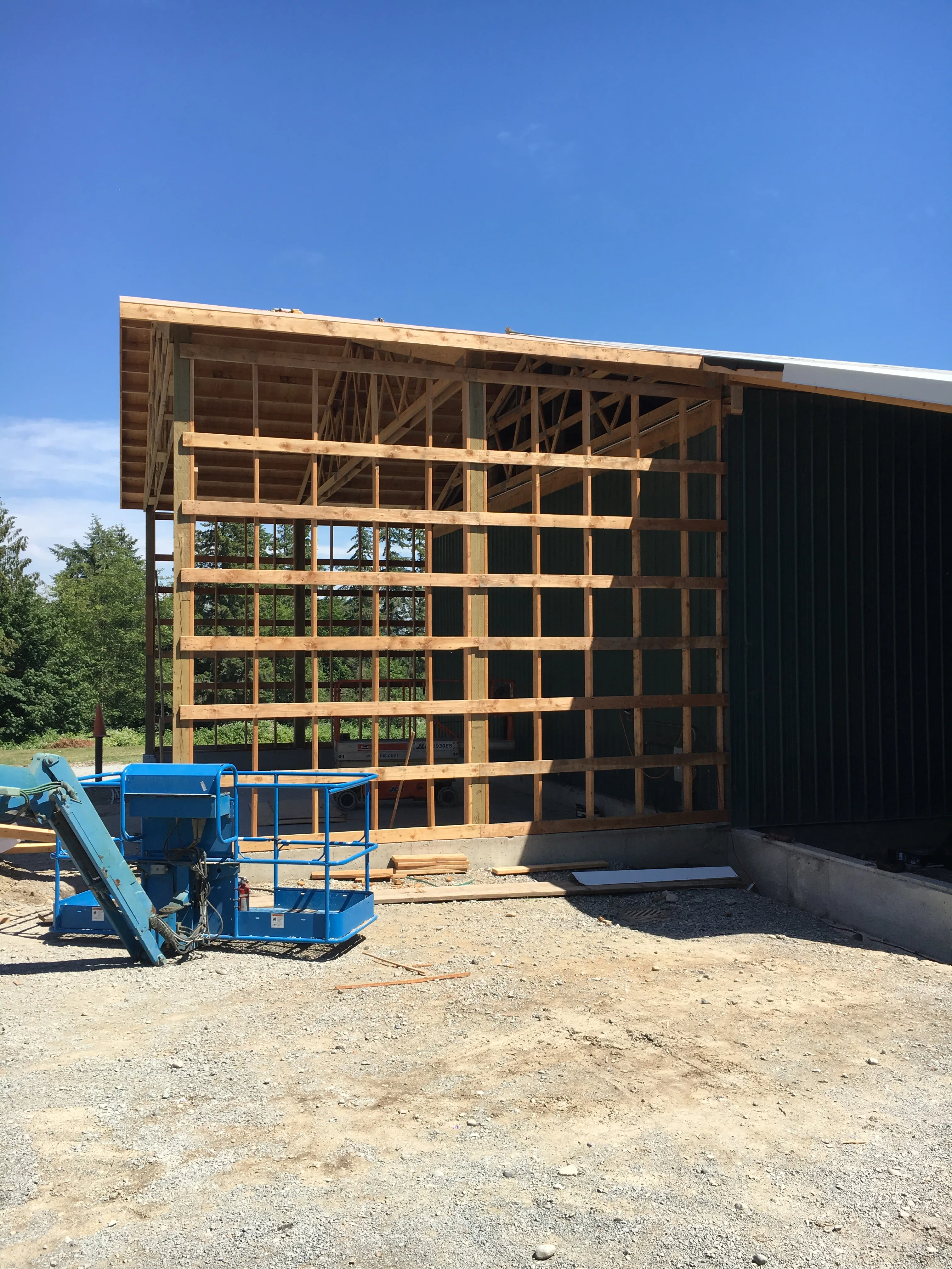 Wood framing for large agricultural building opening with blue lift on site