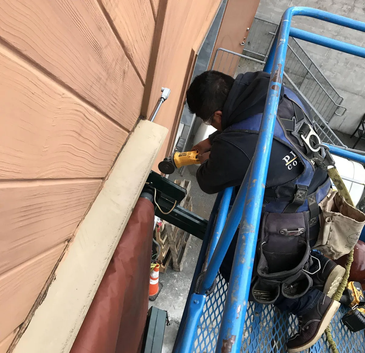 Construction worker on a scissor lift performing exterior panel repair on a commercial building