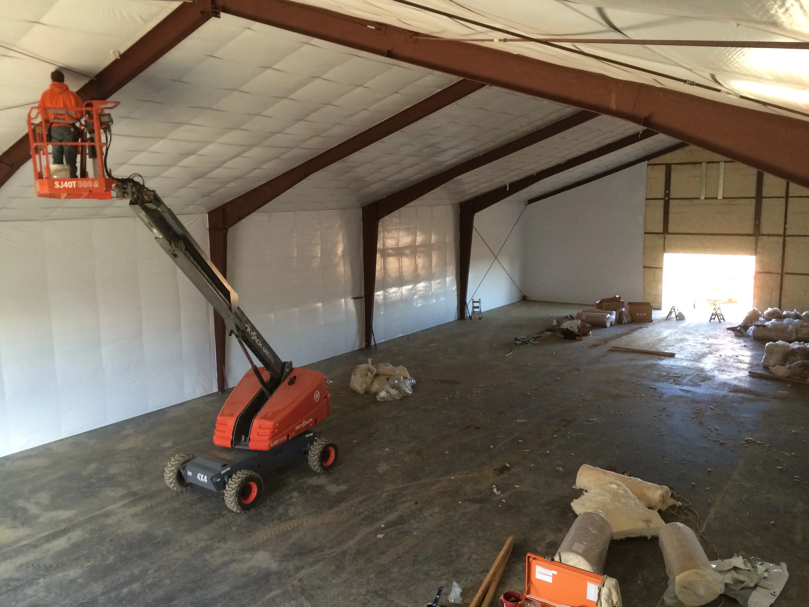 Interior of large steel building with insulation installation and boom lift
