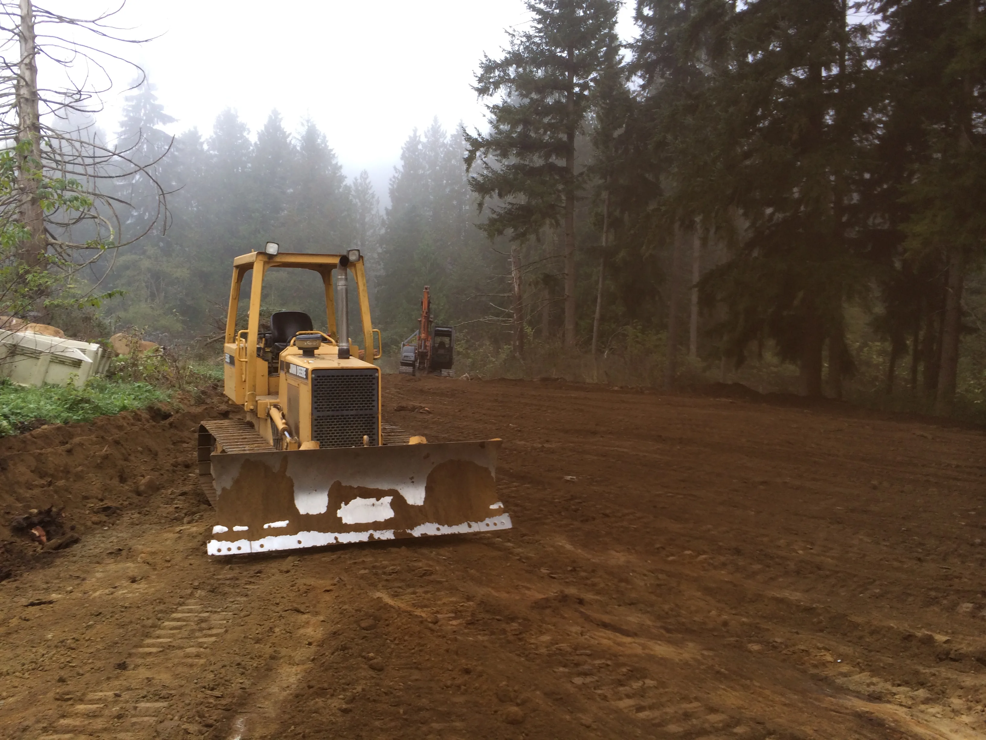Bulldozer grading and site preparation on foggy Pacific Northwest jobsite — Pilchuck Construction