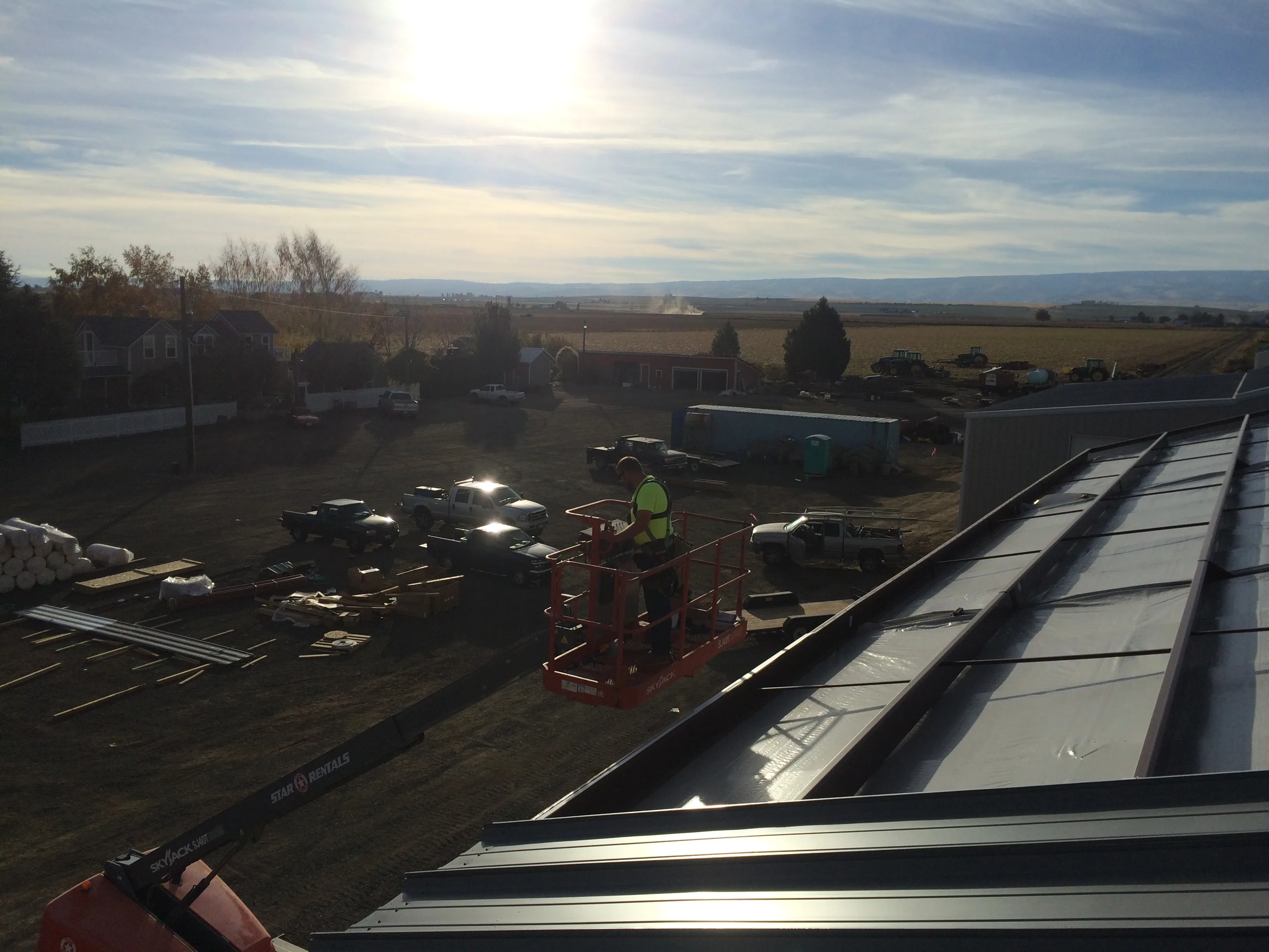 Metal roof panel installation at sunset with crew on roof