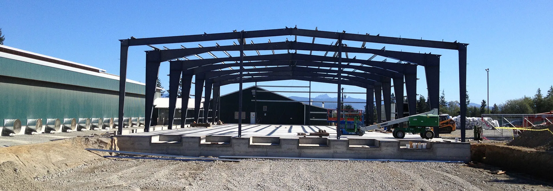 Steel frame going up on concrete foundation with mountains in background