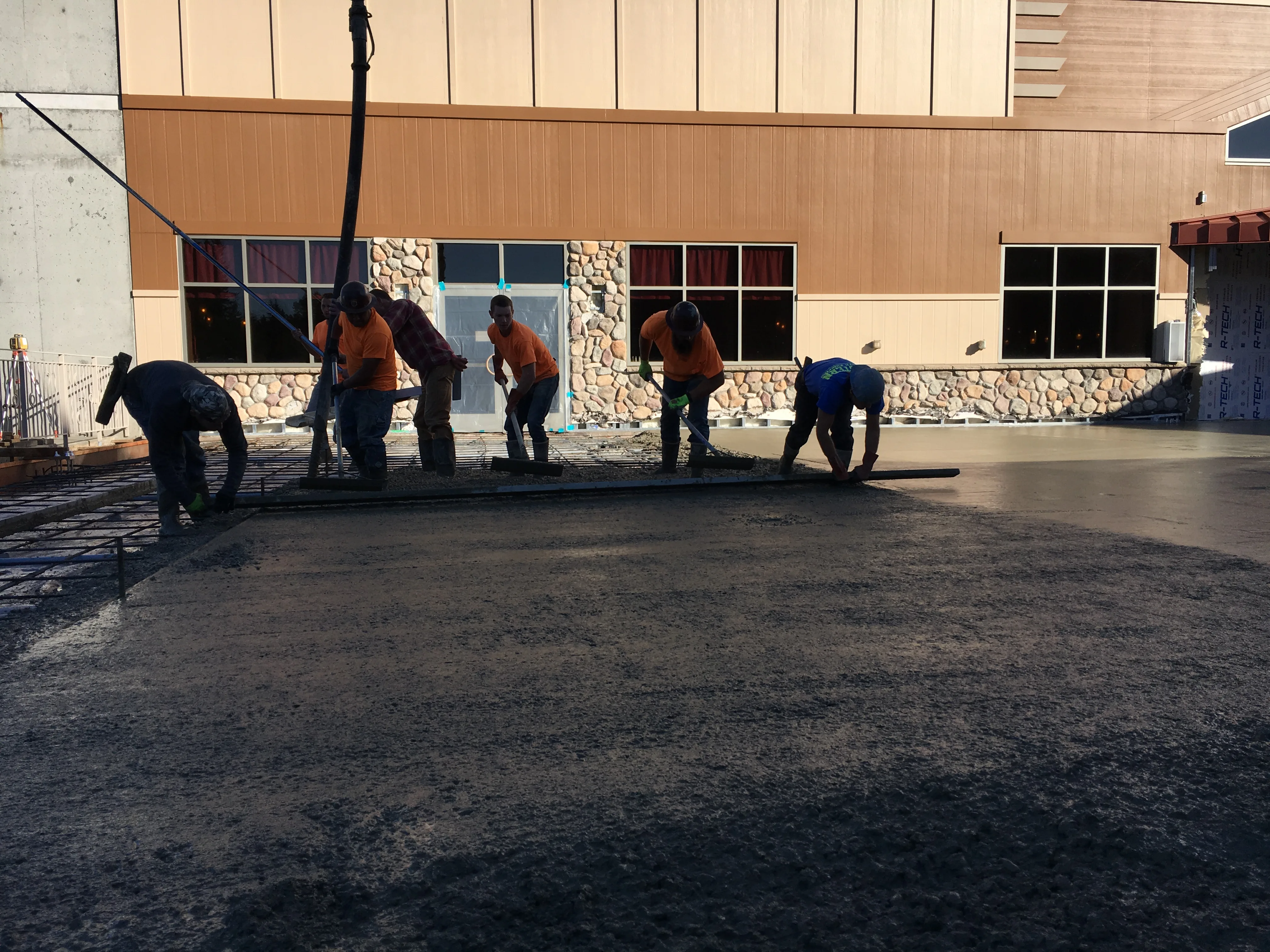 Crew of six workers pouring and finishing a large commercial concrete slab
