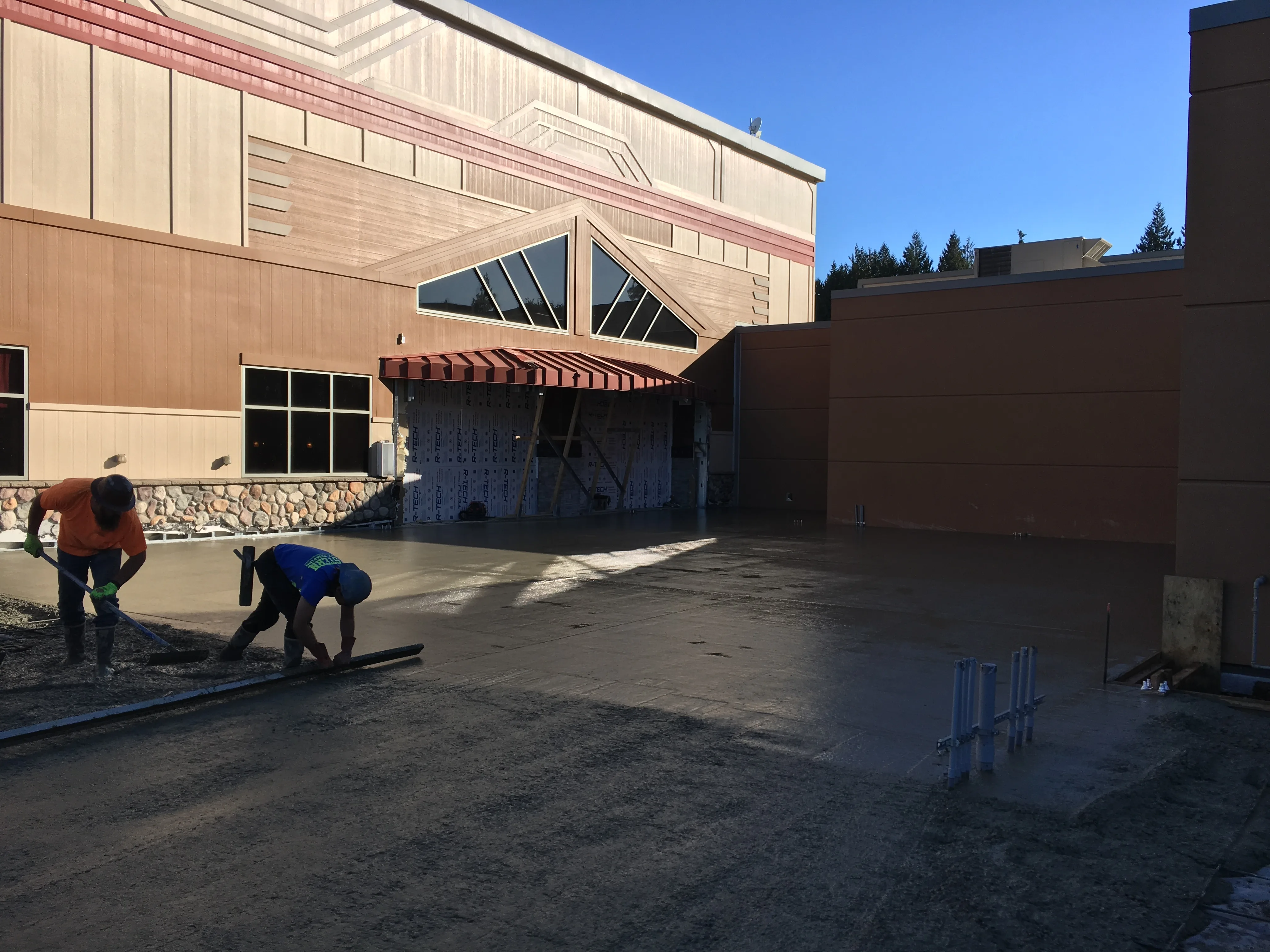 Workers smoothing and finishing freshly poured concrete slab at commercial building